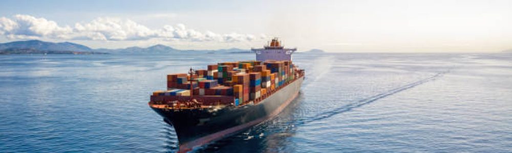 Aerial view of a heavy loaded container cargo vessel traveling over calm, blue sea