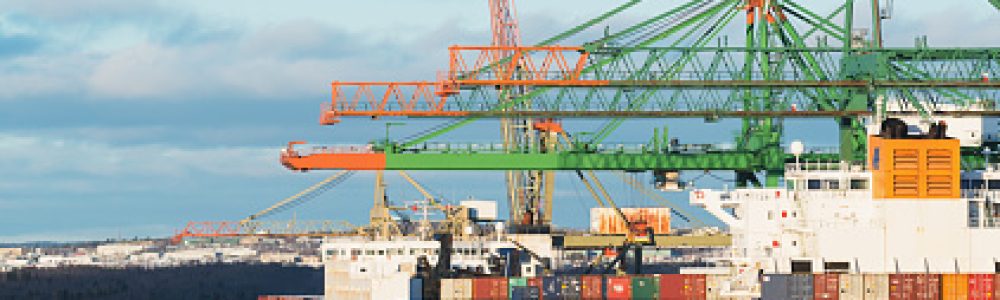 Two tugboats assist a container ship with it's departure from a large container terminal located in Halifax, Nova Scotia.