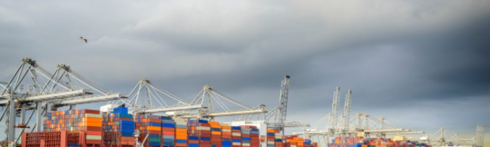 Large cargo ship with shipping containers are loaded with containers in port under a dark sky.